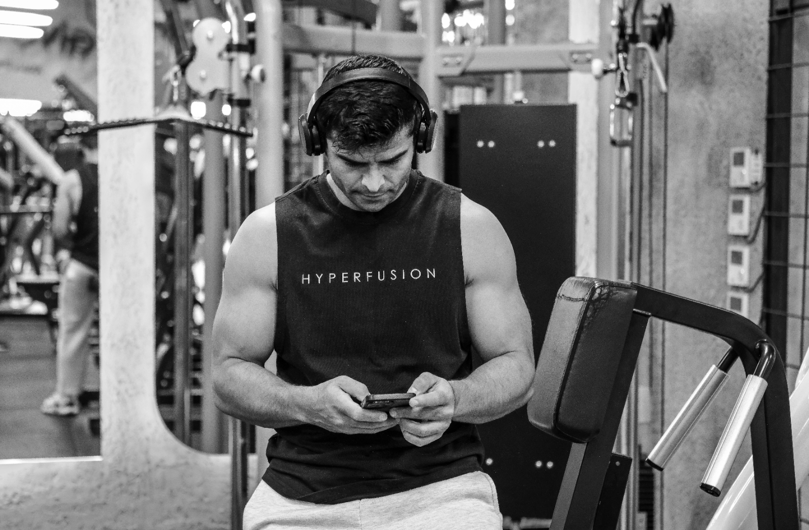 Mann im Fitnessstudio schaut in der Satzpause auf sein Smartphone